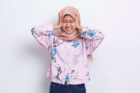 young asian muslim woman covering both ears with hands isolated on white backgroundの写真素材