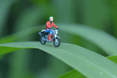 Miniature people figure motorcyclists are touring in the forest