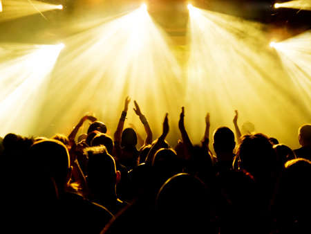 silhouettes of concert crowd in front of bright stage lightsの写真素材