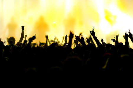 silhouettes of concert crowd in front of bright stage lightsの写真素材
