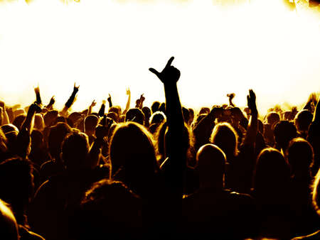 silhouettes of concert crowd in front of bright stage lights