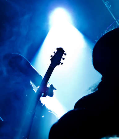 silhouette of guitar player at concert in front of bright stage lightsの写真素材