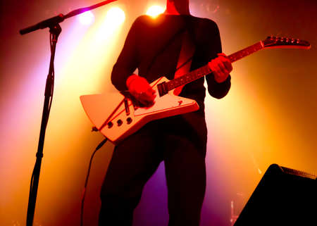 silhouette of guitar player at concert in front of bright stage lightsの写真素材