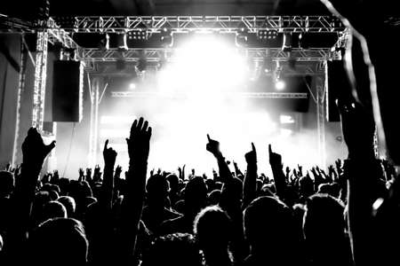 silhouettes of concert crowd in front of bright stage lights