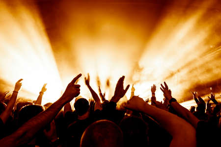 silhouettes of concert crowd in front of bright stage lightsの写真素材