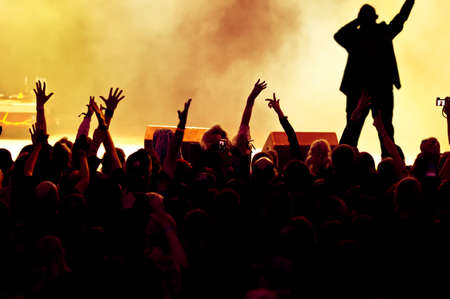 silhouettes of concert crowd in front of bright stage lightsの写真素材