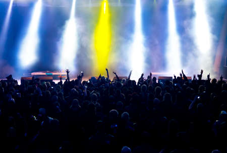 silhouettes of concert crowd in front of bright stage lightsの写真素材