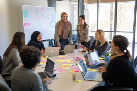 A diverse group of people in an office setting, gathered around the table to brainstorm ideas for their marketing campaign. They're smiling and laughing as they create creative content, with laptops open on every desk. The room is modern and sleek, filled with natural light from large windows. In one corner stands a woman wearing a hijab, leading them through casual conversations while writing down new thoughts onto sticky notes, capturing her confident expression. --ar 3:2 --v 6.1 Job ID: dec165a9-9644-4d94-99ac-3f6bfa8d6c38の素材