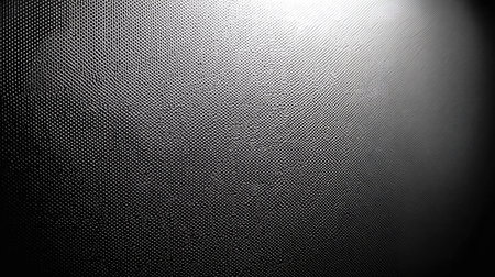 Close-up view of a textured surface with a repeating pattern of dots or small bumps.  The image displays a strong contrast between light and dark areas, highlighting the texture.  The lighting creates a gradient effect, drawing attention to the surface's three-dimensional qualities.の素材