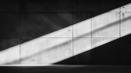 Grayscale image of a concrete wall, with diagonal beams of sunlight creating strong shadows on the surface.の素材