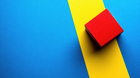 Red cube sits atop a background composed of vibrant blue and yellow stripes. The image showcases a simple geometric shape against a contrasting backdrop. The colors are bold and bright, creating a visually engaging composition.の素材