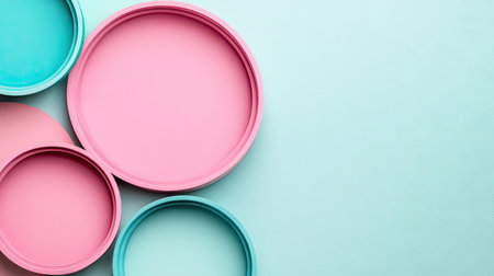 Arrangement of overlapping circles in varying shades of pastel pink and turquoise/teal, creating a visually appealing abstract design. The circles are layered on a light pastel blue surface.の素材