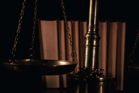 Law and justice, concept of legality, scales of justice on a black background and law books.
