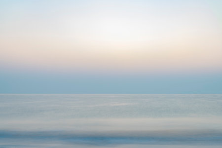 Abstract background of the Indian Ocean at sunrise, featuring a blurry sea landscape with soothing pastel colors. Perfect for presentations or as a versatile backdrop.の写真素材