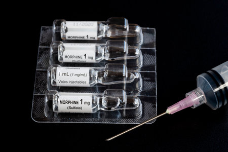 Close-up of liquid morphine sulphate glass vial 1 MG/ML for injections or infusion and syringe,...