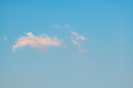 A serene scene featuring a clear blue sky adorned with fluffy white clouds, creating a picturesque backgroundの写真素材