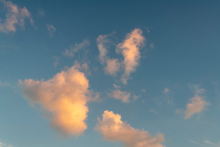 Vibrant blue sky serves as a backdrop to soft, orange and white clouds, making it a versatile background for presentations, website banners, or enhancing your creative projects.の写真素材