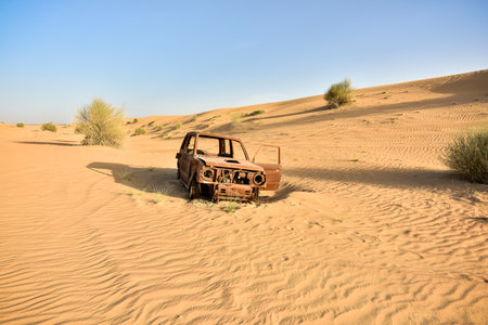 Burned out car wreckage isolated in the desert among sand dunesの写真素材