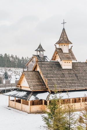 Ancient wooden Slavic church on a snowy landscape. Historical and Architectural Museum in the open air. Kiev, Ukraine, Ancient park Kievskaya Rus'.のeditorial素材