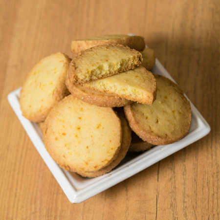 Homemade lemon cookies in a white saucer on a wooden table. Square picture, closeup.の写真素材