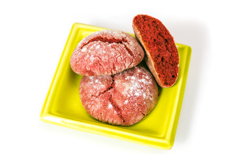 Red cookies with icing sugar on a green plate isolated on white backgroundの写真素材