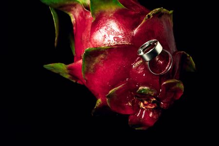 Wedding rings white gold on an exotic fruit close-up, black backgroundの写真素材