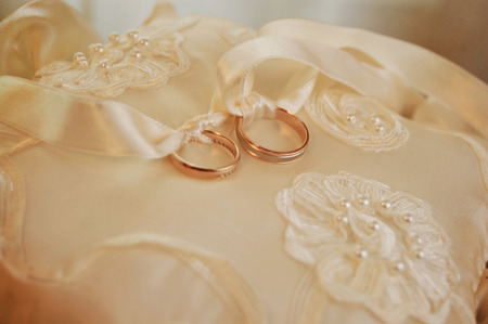 wedding gold rings lie on a cushion for ringsの写真素材