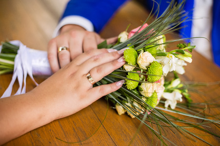 groom with the bride holding their hands on a bouquet with rings flowersの写真素材