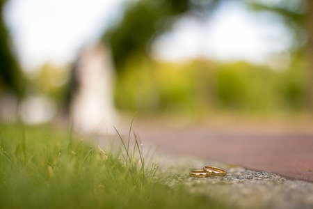 gold rings of the bride and groom are lying on the asphalt and blurredの写真素材