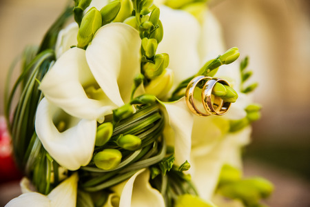 a bridal bouquet with wedding rings rests on a stone in the streetの写真素材