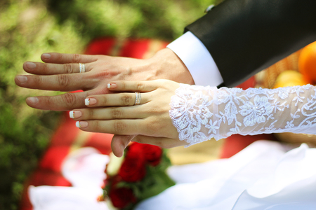 The groom and the bride are holding hands with wedding ringsの写真素材