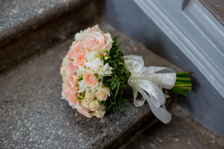 a bridal bouquet of bride lies on a stone stair in the roomの写真素材