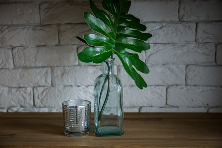 the palm leaves stand in a green vase on a wooden shelfの写真素材