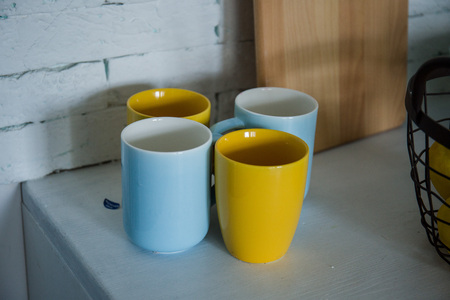 yellow and blue cups stand on the table in the kitchenの写真素材