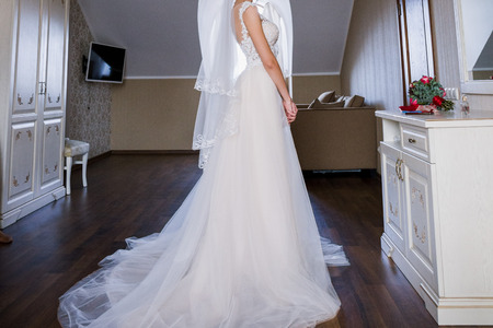 the bride is standing in the dress in the roomの写真素材