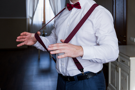 the groom holds his hands suspenders in a suitの写真素材