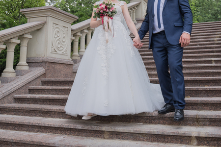bride and groom walk together by the hand in the parkの写真素材