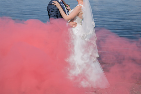 bride and groom stand together against the water