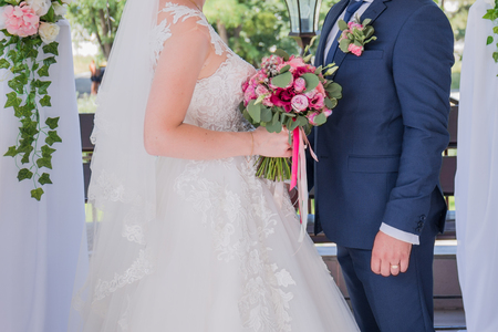 bride and groom stand together under the arch of the wedding ceremonyの写真素材