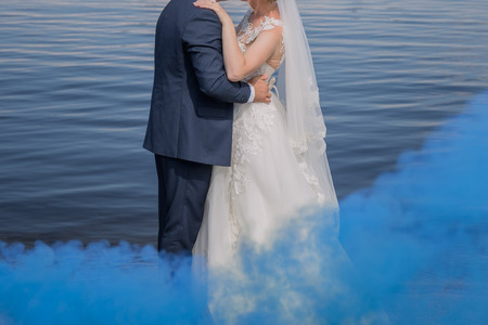 bride and groom stand together against the waterの写真素材