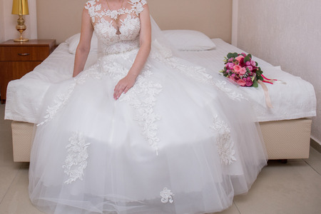 the bride in a wedding dress sits in the room on the bedの写真素材