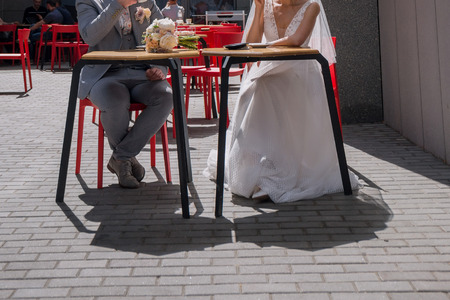 the bride and groom sit at a table in a cafe drinking coffeeの写真素材