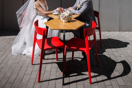 the bride and groom sit at a table in a cafe drinking coffeeの写真素材