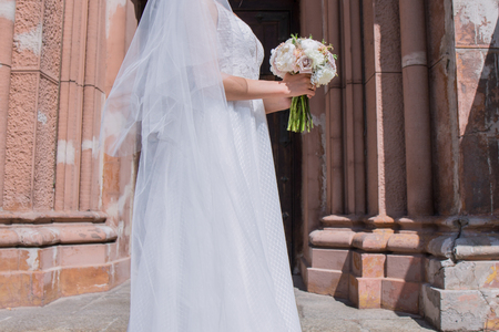 bride with wedding bouquet and veil near the churchの写真素材