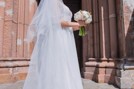 bride with wedding bouquet and veil near the churchの写真素材