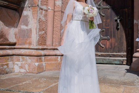 bride with wedding bouquet and veil near the churchの写真素材