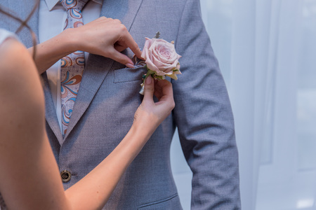 the bride is putting on the boutonniere
