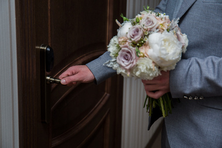 the groom opens the door with a bouquet in their handsの写真素材