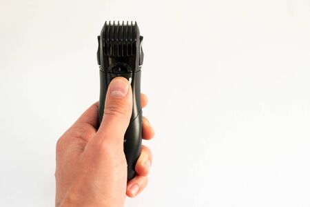 electric trimmer in hand on a white background