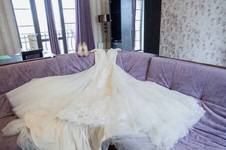 wedding dress with shoes lies on sofaの写真素材